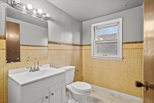 bathroom with vanity, tile walls, and toilet