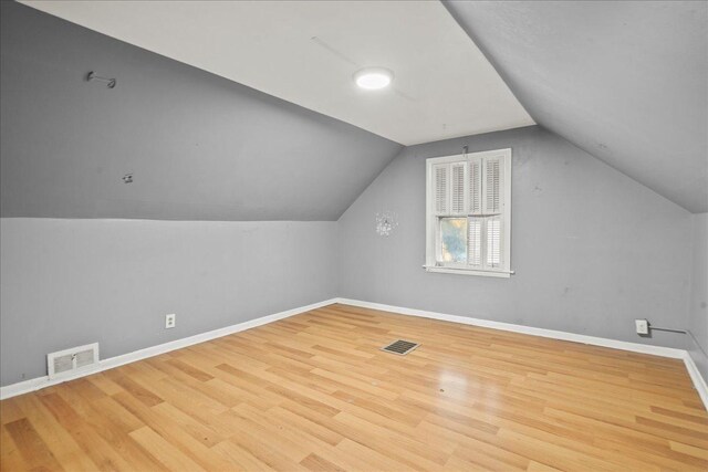 additional living space with light wood-type flooring and vaulted ceiling