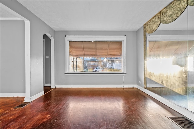 empty room featuring a textured ceiling and dark hardwood / wood-style floors