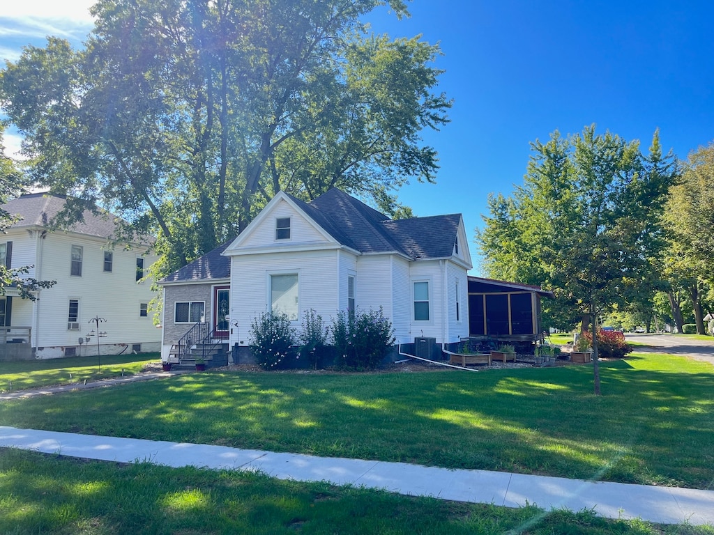 view of front of house featuring a sunroom and a front lawn