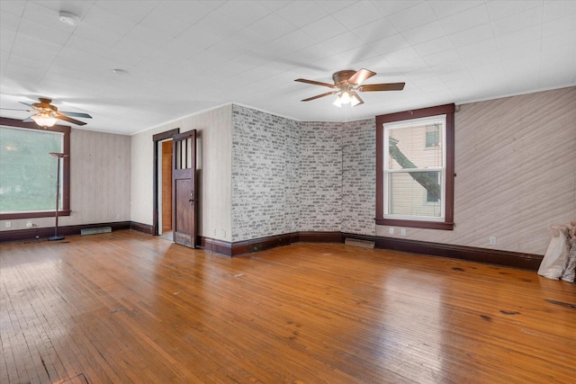 empty room featuring plenty of natural light, baseboards, ceiling fan, and hardwood / wood-style flooring