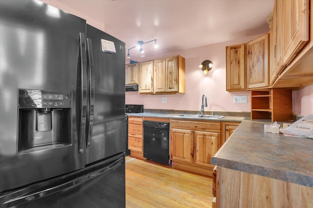 kitchen featuring a sink, light brown cabinetry, light wood-style flooring, dark countertops, and black appliances