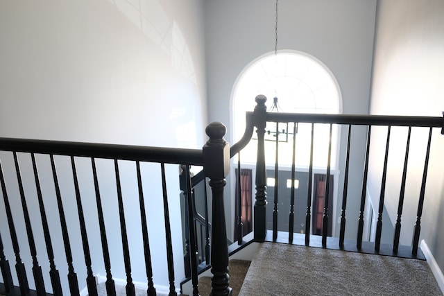 stairs featuring a towering ceiling, a notable chandelier, and carpet flooring