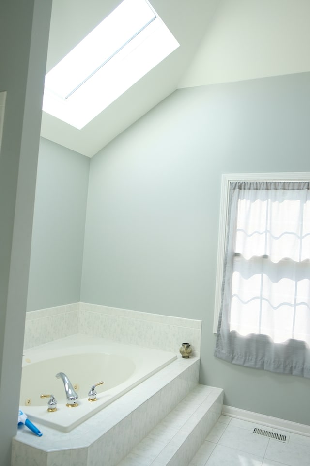 bathroom featuring tile patterned floors, lofted ceiling with skylight, and a relaxing tiled tub