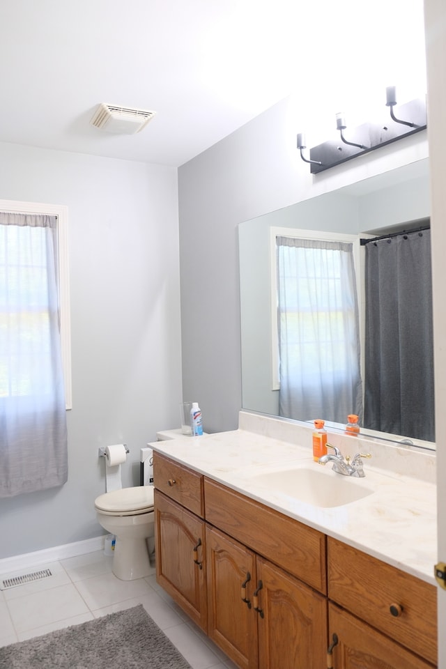 bathroom featuring a wealth of natural light, vanity, toilet, and tile patterned flooring