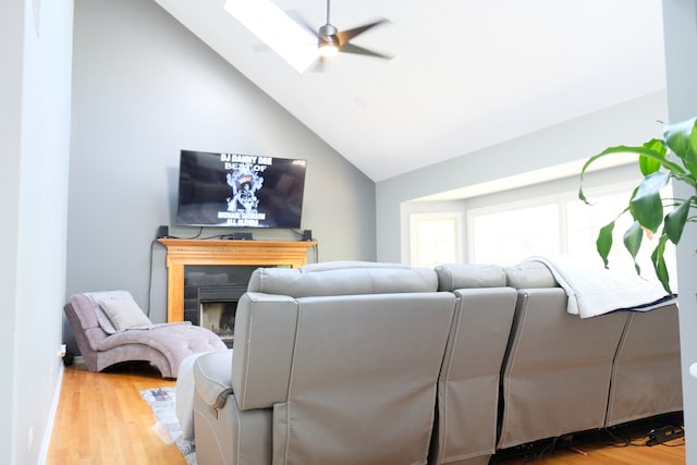 living room with ceiling fan, high vaulted ceiling, wood-type flooring, and a skylight