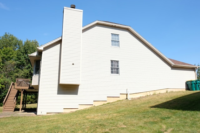 view of side of home featuring a wooden deck and a yard