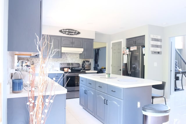 kitchen featuring appliances with stainless steel finishes, light tile patterned flooring, a center island, and backsplash