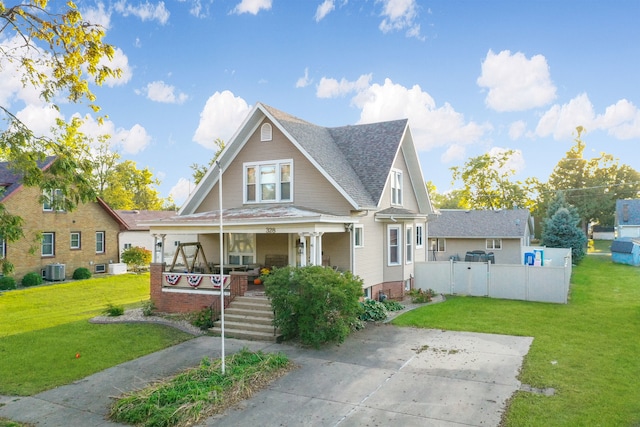 view of front of property featuring covered porch, a front yard, and central AC unit