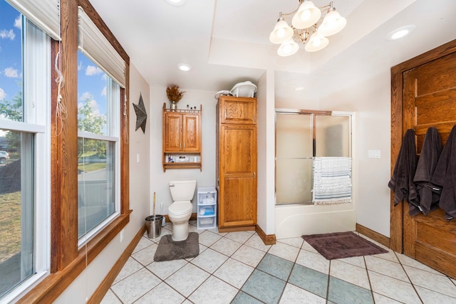 bathroom with tile patterned floors, toilet, an inviting chandelier, a raised ceiling, and combined bath / shower with glass door