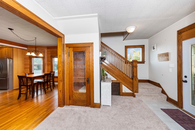 foyer entrance featuring light hardwood / wood-style floors, a textured ceiling, a chandelier, and plenty of natural light