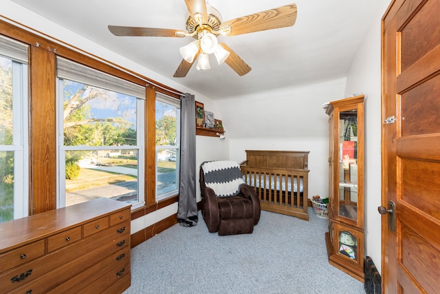 bedroom with light carpet, vaulted ceiling, a nursery area, and ceiling fan