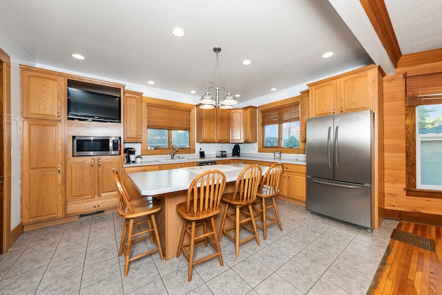 kitchen featuring a kitchen island, a breakfast bar area, beam ceiling, stainless steel appliances, and a chandelier