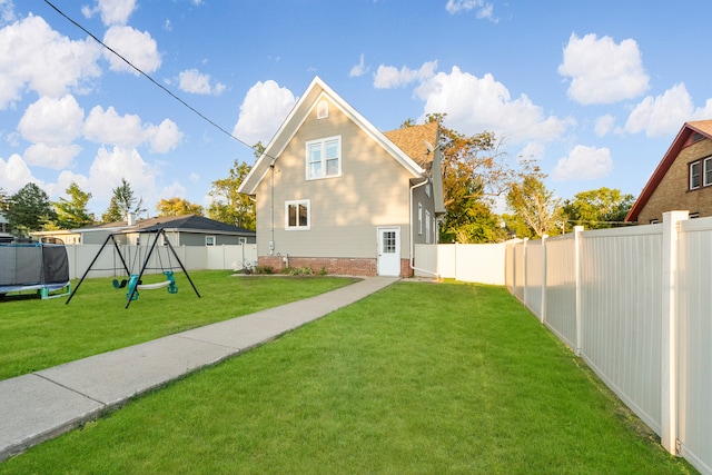 rear view of house with a lawn and a playground