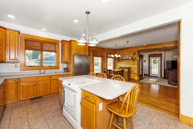 kitchen with a kitchen island, light wood-type flooring, an inviting chandelier, white electric range oven, and stainless steel refrigerator