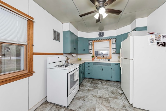 kitchen featuring ceiling fan, sink, white appliances, and blue cabinets