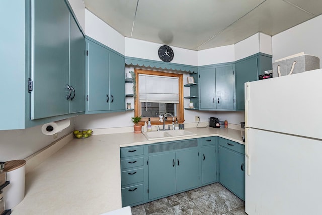 kitchen with sink, blue cabinets, and white refrigerator