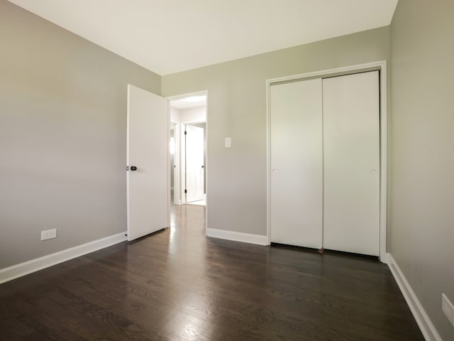 unfurnished bedroom with a closet and dark wood-type flooring