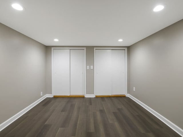 unfurnished bedroom featuring two closets and dark hardwood / wood-style floors