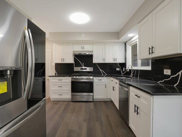 kitchen featuring decorative backsplash, white cabinets, appliances with stainless steel finishes, and dark hardwood / wood-style flooring