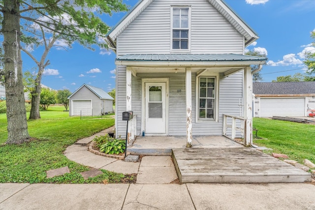 view of front of home with an outbuilding, a garage, covered porch, and a front yard