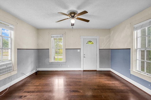 unfurnished room with a textured ceiling, dark wood-type flooring, ceiling fan, and plenty of natural light