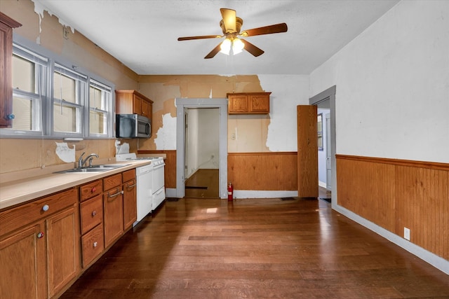 kitchen with dark hardwood / wood-style floors, sink, wooden walls, white appliances, and ceiling fan