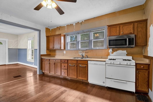 kitchen featuring white appliances, dark hardwood / wood-style flooring, a textured ceiling, ceiling fan, and sink