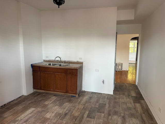 interior space with heating unit, sink, and dark hardwood / wood-style flooring