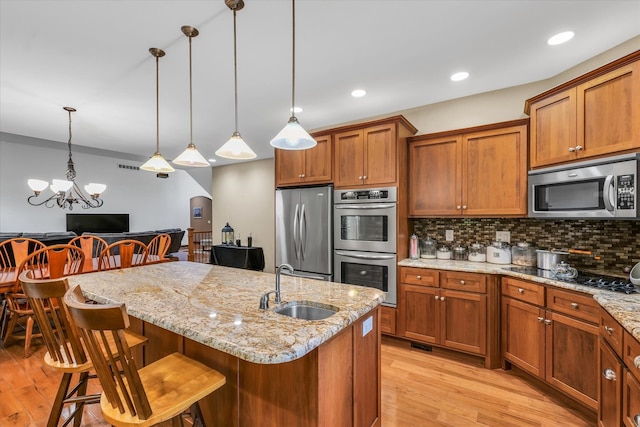 kitchen with light wood-type flooring, a kitchen breakfast bar, sink, and stainless steel appliances