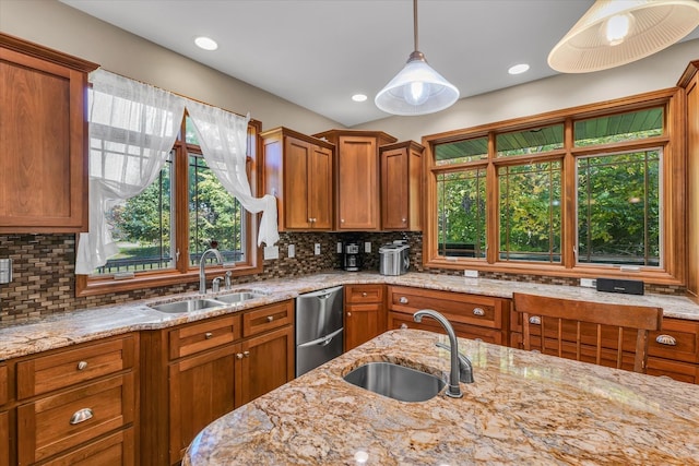 kitchen featuring light stone counters, decorative light fixtures, sink, and tasteful backsplash