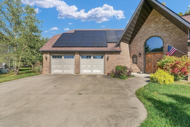 view of front facade featuring a garage, solar panels, and a front lawn