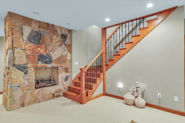 staircase with a stone fireplace and carpet