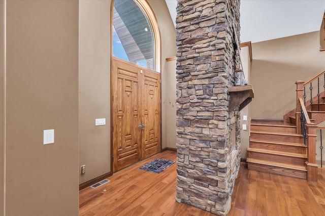 foyer entrance featuring light wood-type flooring and a towering ceiling