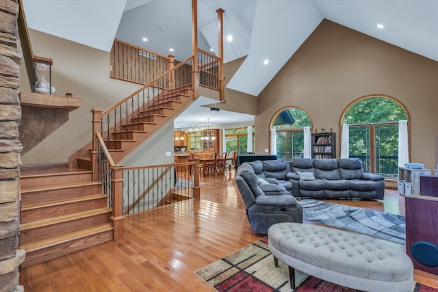 living room with wood-type flooring, a notable chandelier, and high vaulted ceiling