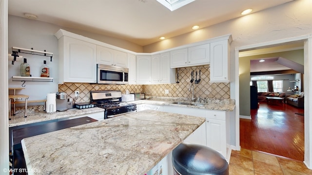 kitchen with white cabinetry, range with gas cooktop, light stone countertops, light wood-type flooring, and sink