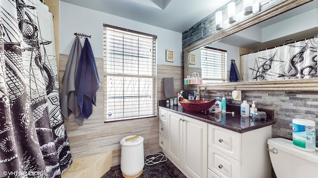 bathroom with vanity, tile walls, and toilet