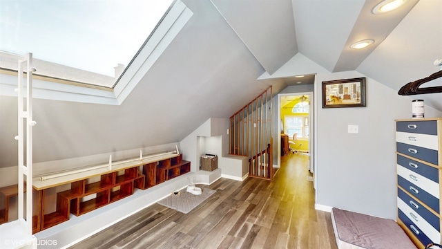 additional living space featuring wood-type flooring and vaulted ceiling with skylight