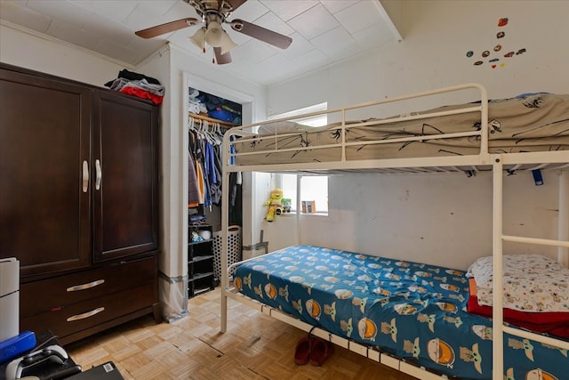 bedroom with a closet, light parquet floors, ceiling fan, and crown molding