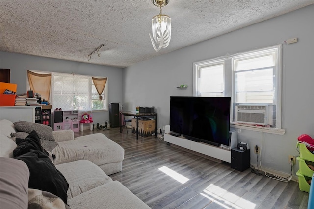 living room with cooling unit, hardwood / wood-style flooring, track lighting, and a textured ceiling