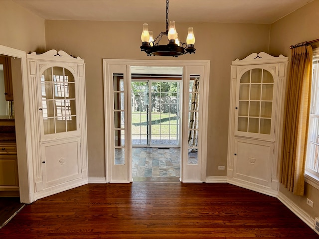 unfurnished dining area featuring an inviting chandelier, dark hardwood / wood-style floors, and plenty of natural light