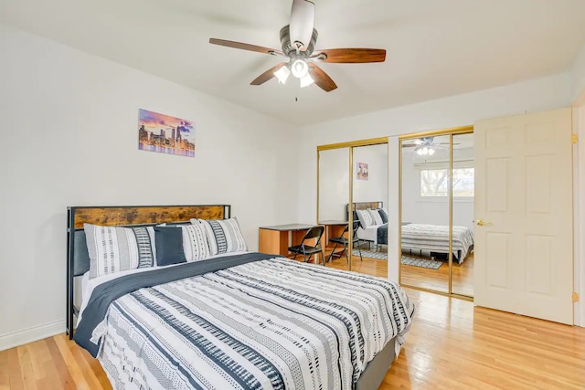 bedroom with wood-type flooring, two closets, and ceiling fan