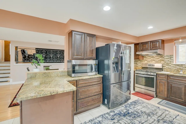 kitchen with light wood-type flooring, sink, backsplash, appliances with stainless steel finishes, and light stone countertops