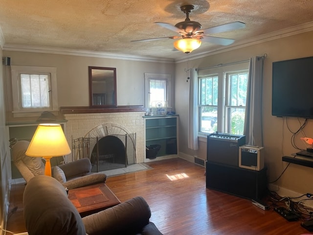 living room featuring crown molding, wood-type flooring, a fireplace, and ceiling fan