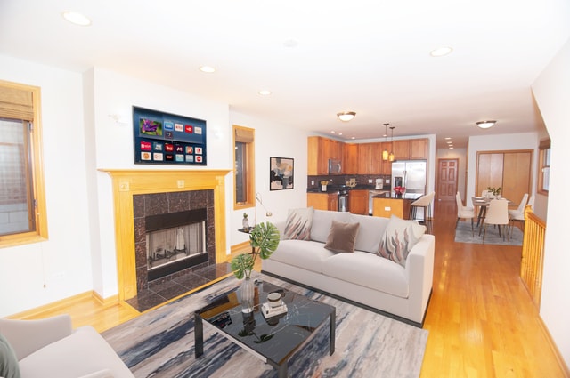 living room with light wood-type flooring and a tiled fireplace