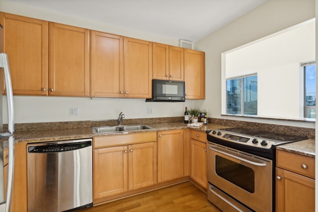 kitchen with light wood-type flooring, appliances with stainless steel finishes, and sink