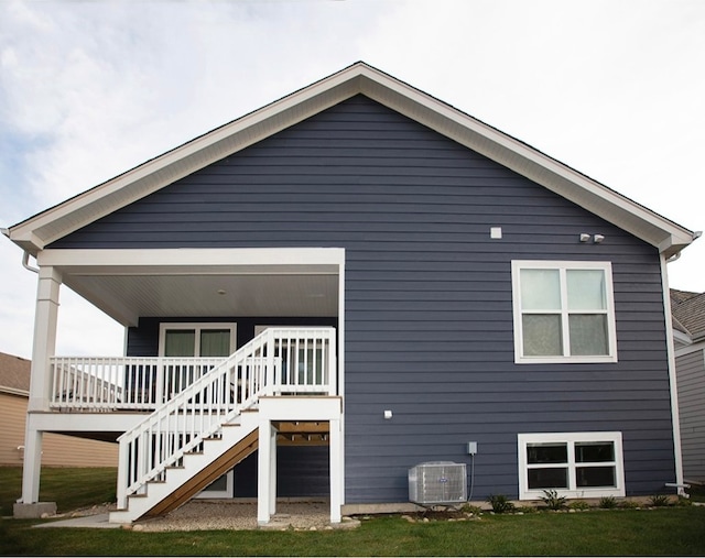 rear view of house featuring a deck, a yard, and central AC