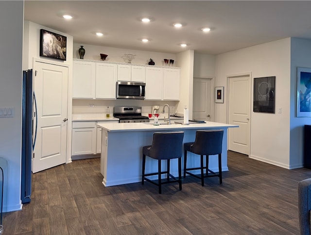 kitchen featuring white cabinets, an island with sink, appliances with stainless steel finishes, and dark hardwood / wood-style flooring