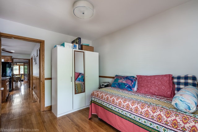 bedroom with black fridge and hardwood / wood-style flooring