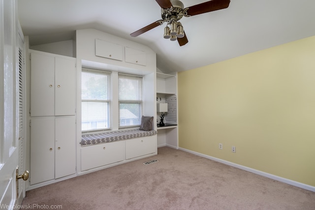 interior space with ceiling fan, light colored carpet, and vaulted ceiling